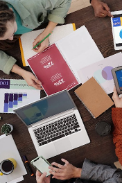 An overhead view of a team reviewing various charts, graphs, and digital devices on a wooden table.